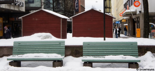 Green benches covered in snow on the shopping street in Hml