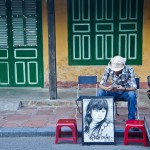Local artist waiting for tourists to have their portraits drawn in Hoi An.