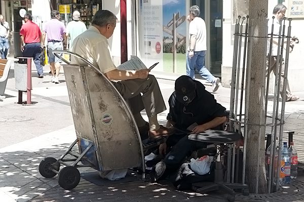 Reading paper while having his shoes polished