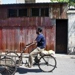 A local cycling past the mural of kids on bicycle (background).