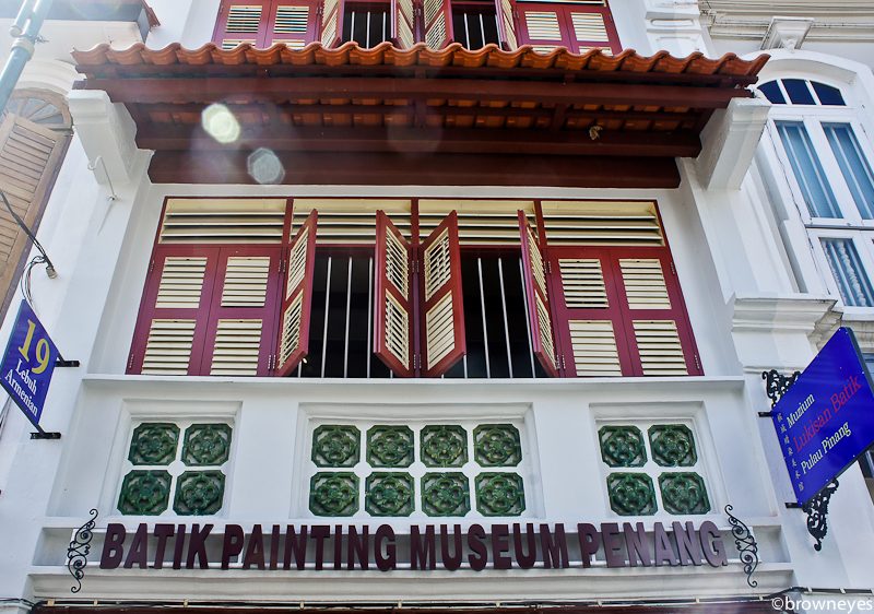 This batik painting museum has red wooden windows.